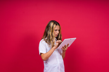 Online school app. Schoolgirl showing tablet computer Empty Screen Over red Background. Studio Shot