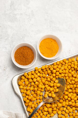 Indian traditional crispy, salty, savory snack - roasted chickpeas covered with spices curry powder, garam masala and turmeric on a baking tray. Flat lay, top view