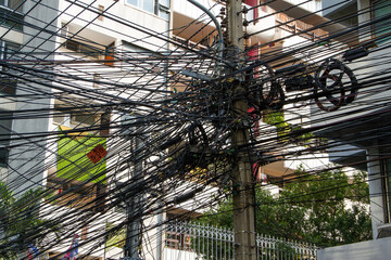 Chaos of cables and wires in Bangkok, Thailand, electric and telephone wires wound on a lamppost