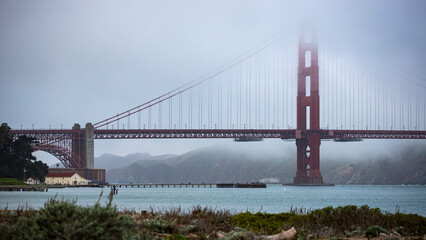 panorama of the golden gate bridge in san francisco during foggy weather; the famous red bridge emerging from behind the clouds, gloomy photo of the golden gate bridge