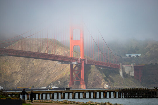 panorama of the golden gate bridge in san francisco during foggy weather; the famous red bridge emerging from behind the clouds, gloomy photo of the golden gate bridge