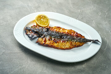 Grilled mackerel in a white plate on a concrete background