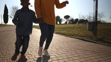 single mother with her little african american son running in the park on a sunny day