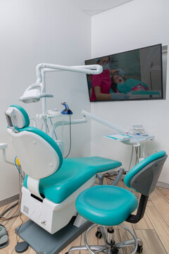 Vertical image of a dental office with a screen on the wall.