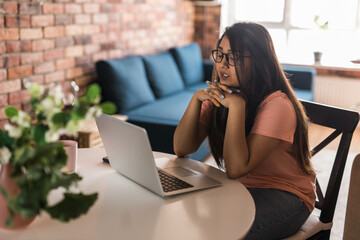 Latino or indian woman use their laptop in living room to make video calls. Video call and online chat with family