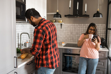 Millennial couple in quarrel and woman with smartphone ignoring each other having breakfast together at home, gadget overuse - communication problem in family