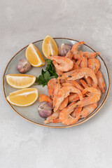 frozen raw shrimps with lemon and garlic on a gray rock  background 