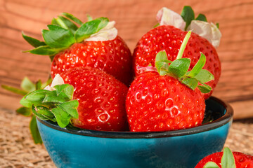 Ripe strawberries with water drops in a bowl in a bowl, close-up, natural sunlight, strawberry spring season