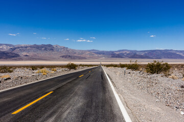 State Route 190 crossing Panamint Valley in Death Valley National Park, California, United States. Empty desert road in Death Valley with clear blue sky.