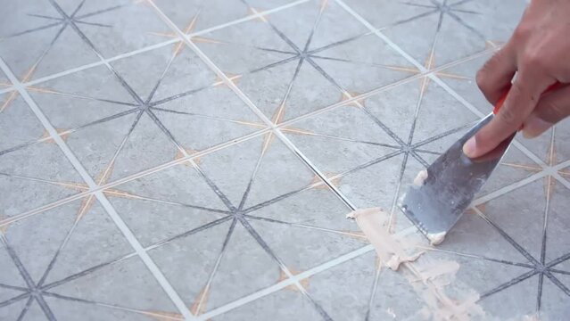 Tiler laying the ceramic tile on the floor. Grouting ceramic tiles. Professional worker makes renovation. Construction. Hands of the tiler. Home renovation and building new house.	