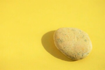 Fototapeta na wymiar Beige pebble stone at yellow sunny table