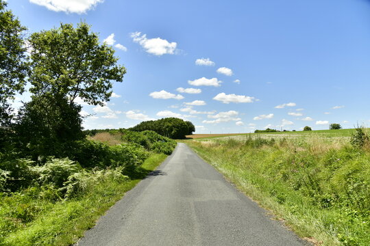 Route de campagne sous les cumulus de beau temps aux environs du bourg de Champagne au P&eacute;rigord Vert 