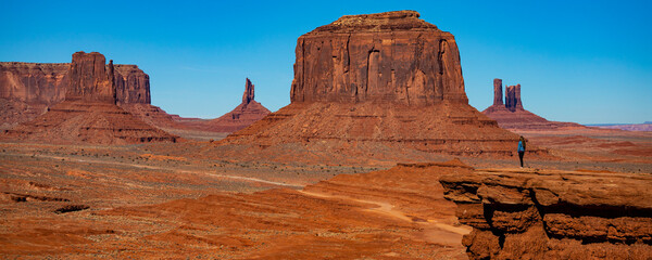 Beautiful girl stands on famous John Ford Point and admires massive mountains in Monument Valley Navajo Tribal Park, Utah, Arizona, USA
