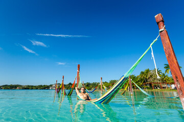 Man on hammock in Bacalar lagoon Mexico - 574405913