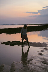 A man on the ocean at sunset, reflected in the water.