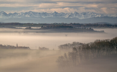 Sunrise in the mist in the Gers department in France with the Pyrenees in the background