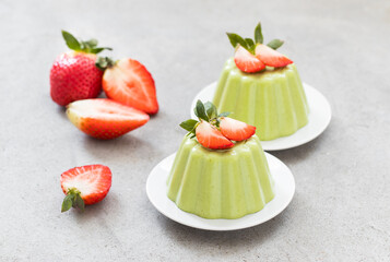 Spinach cream pudding, Panna Cotta with strawberries, on a plate. Light grey background