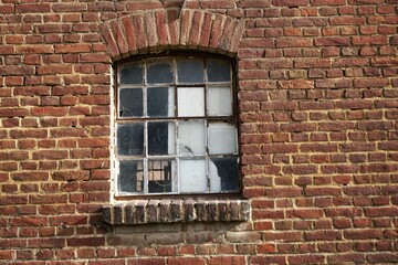 Fototapeta na wymiar Alte rotbraune Backsteinfassade mit Kästchenfenster von Bauernscheune bei Sonne am Mittag im Winter
