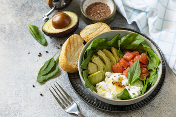 Classic breakfast, brunch - with poached egg, avocado, arugula, flax seeds and salted salmon on a gray background.  Copy space.