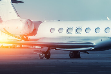 Scenic side close view modern luxury expensive private jet plane parked airport taxiway hangar warm colorful dramatic evening sunset sun light sky background. Executive aicraft vip travel concept