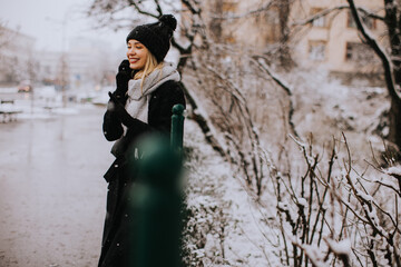 Young woman in warm clothes using mobile phone on a winter day