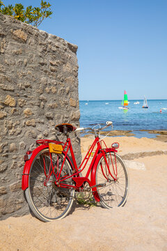 Vieux vélo rouge en bord de mer sur les plages de Bretagne en France.