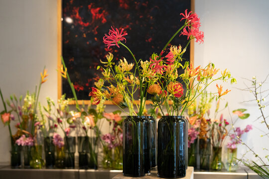 Decorative glass vases with flowers. flame lilis (Gloriosa superba) in the foreground.