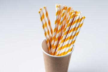 Disposable cardboard biodegradable cup on a white table with a straw.
