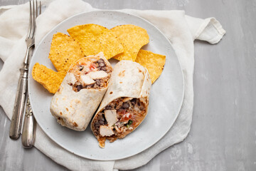 Mexican beef burrito on small plate with chips nachos