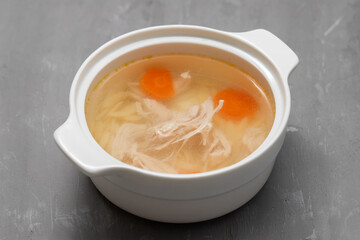 bowl of chicken broth with chicken and carrot in ceramic