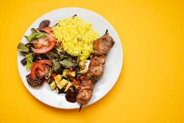 Grilled meat on stick, vegetables, salad and boiled rice
