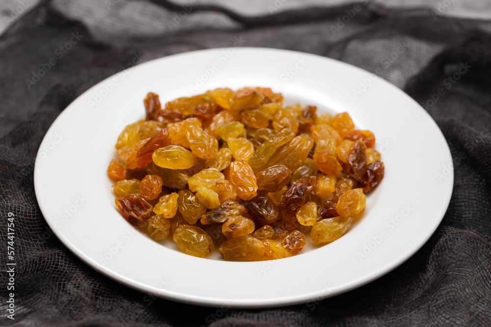 Poster Yellow golden raisins in white ceramic plate