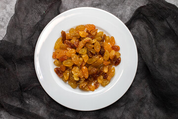 Yellow golden raisins in white ceramic plate