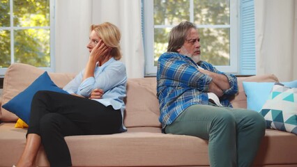Upset annoyed mature family couple sit on couch turn away from each other. Realtime - Powered by Adobe