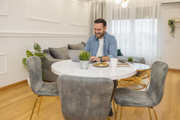 Smiling businessman working on laptop at home office