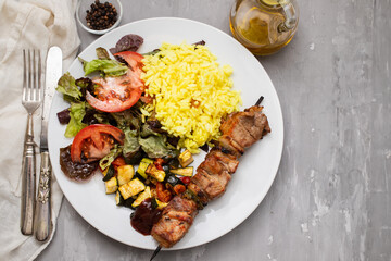 Grilled meat on stick, vegetables, salad and boiled rice