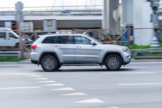 Silver Jeep Grand Cherokee WK2 car moving on the street. Compliance with speed limits on road concept. Dynamic exterior image