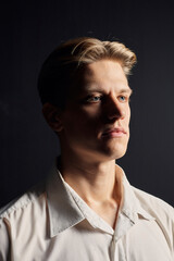 portrait of a handsome man in a white shirt on a black background, looking seriously at the camera