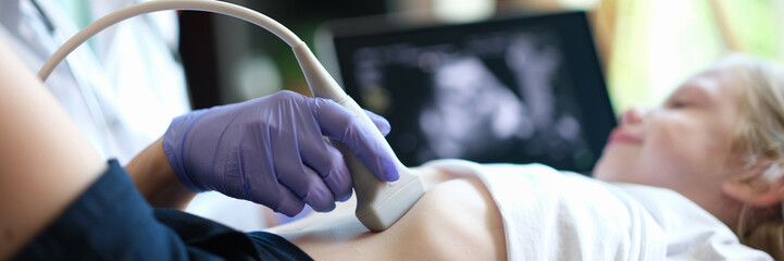 Doctor make ultrasound of abdominal cavity for girl using scanner in clinic