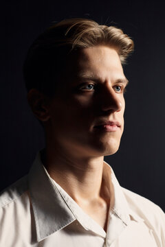 portrait of a handsome man in a white shirt on a black background, looking seriously at the camera