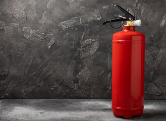 Fire extinguisher on the background of a black texture wall. Red fire extinguisher indoors on the...
