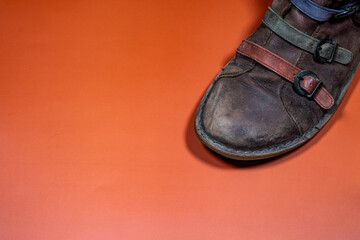 Worn-out Shoe Detail with Colorful Leather Strips on Brown Background