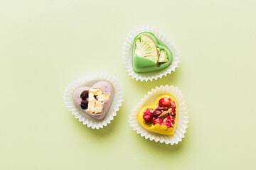 chocolate sweets in the form of a heart with fruits and nuts on a colored background. top view with space for text, holiday concept