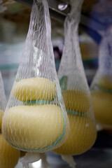 Delicious fresh Caciocavallo and Scamorza cheese hanging. Italian cheeses close up. The cheeses are...