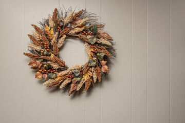 Autumn wreath with muted colors on white wood wall