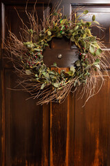 Wooden front door decorated with branch wreath