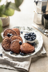Healthy breakfast. Pancakes with fresh blueberries and mint leaves served with coffee in morning light, greenery in blur