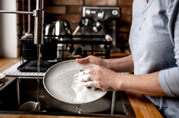 Obraz na płótnie Canvas Girl washing dishes at kitchen at home