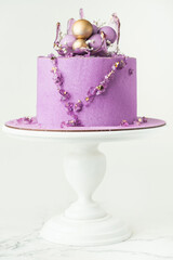 Wedding cake with violet cream cheese frosting decorated with caramel vase and golden chocolate...