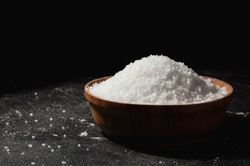 Fototapeta na wymiar Coarse white salt in a wooden bowl on the black background